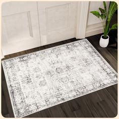 a white and gray area rug on the floor next to a potted green plant