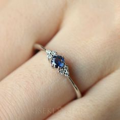 a woman's hand with a blue and white diamond ring on her left finger