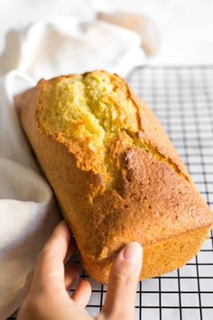 a person holding a loaf of bread on top of a cooling rack next to a white towel