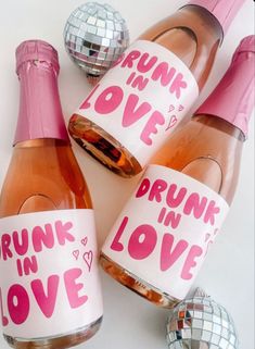 three bottles of pink wine with the words drunk in love on them and disco balls