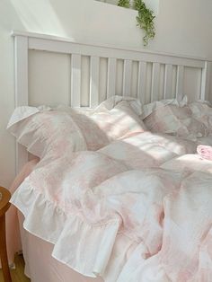 a bed with white sheets and pink pillows