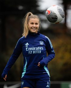 a woman is playing with a soccer ball in the air and smiling at the camera