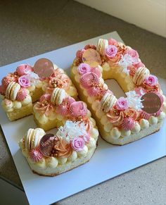 a number shaped cake on top of a white plate with pink flowers and hearts around it