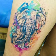 an elephant tattoo on the thigh with watercolor splashs and paint splatters