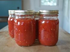 two jars filled with red sauce sitting on top of a wooden table