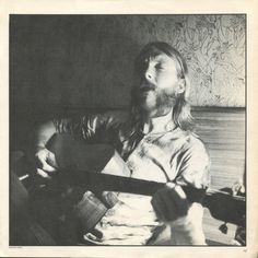 a man with long hair holding a guitar in his right hand and looking up at the sky