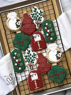 decorated cookies are on a cooling rack with white and green frosting, red and gold trimmings