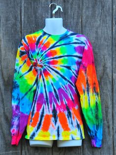 a colorful tie - dyed shirt hanging on a wooden wall