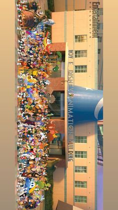 a crowd of people standing in front of a tall building with a water slide on it's side