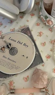 several items are laying on a table with pink flowers and silver objects around them, including a cd