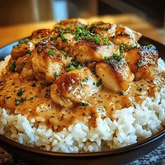 a plate with rice, chicken and sauce on it sitting on a counter top next to a wooden table