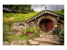 an image of a hobbot house in the middle of grass and rocks with stairs leading up to it