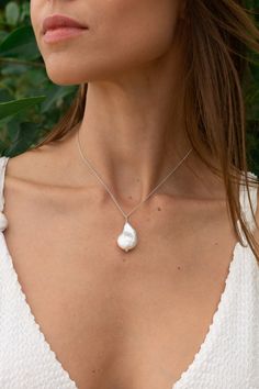 This sterling silver necklace features a stunning baroque freshwater pearl that exudes elegance and grace. Known for its ability to promote purity, integrity and tranquillity, the pearl gives the wearer a sense of serenity.  In addition, the Balinese blessing of the necklace adds spiritual strength and invites positive energy and protection into your life. It is believed that wearing this necklace can enhance your intuition and stimulate your inner wisdom. It helps you to connect with your higher self and your spiritual essence. Sterling Silver Pearl Drop Necklace, Sterling Silver Pearl Drop Necklace Pear Shape, Delicate Pear-shaped Silver Necklace, Silver Baroque Pearl Necklace For Wedding, Wedding Pearl Necklace With Sterling Silver Clasp, Delicate Silver Baroque Pearl Jewelry, White Pearl Pendant Necklace In Spiritual Style, Spiritual White Adjustable Pearl Necklace, Spiritual White Pearl Pendant Necklace