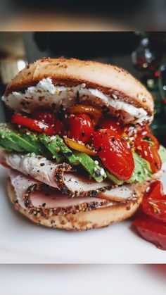 a sandwich with tomatoes, lettuce and other toppings on it next to a christmas tree