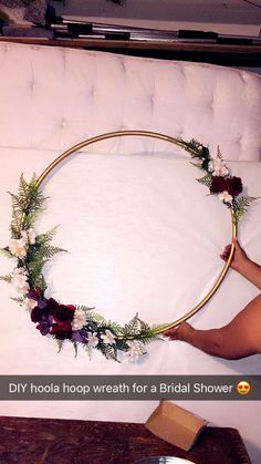 a woman laying on top of a bed holding a hoop with flowers in the middle