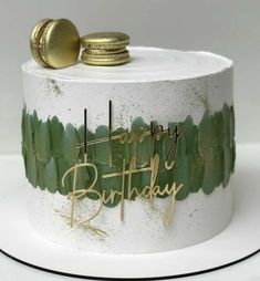 a white cake with green frosting and gold decorations on it's top that says happy birthday