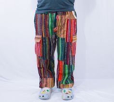 a person wearing colorful pants and shoes standing in front of a white background with his hands on his hips