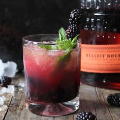 a bottle of blackberry iced tea next to a glass filled with blackberries