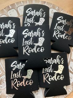 six black coasters with white writing on them sitting on a wooden table in front of a plate