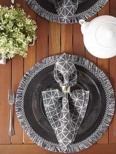 the table is set with black and white plates, silverware, and floral centerpieces