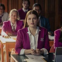 a woman sitting at a desk in front of other people