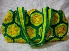 a green and yellow crocheted purse sitting on top of a white tablecloth