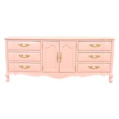 a pink dresser with gold trimmings on the top and drawers, against a white background