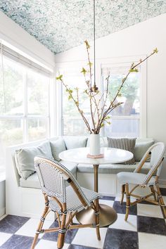 a white table and chairs in front of a window with a potted plant on it