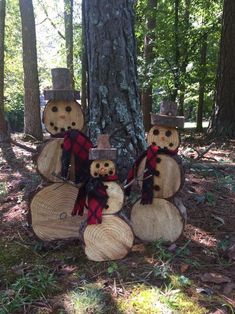 three snowmen made out of logs in the woods