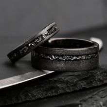 two wedding bands are sitting next to each other on top of a piece of wood