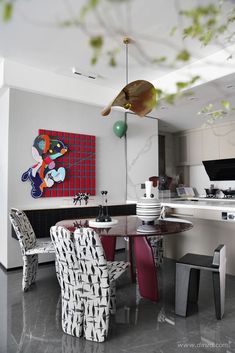 a dining room table with chairs and a painting on the wall behind it in an open kitchen