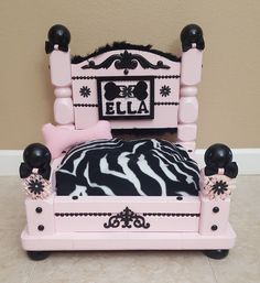 a pink and black doll bed with zebra print sheets