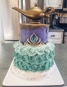 a three tiered cake with blue and green frosting on top, sitting on a white plate