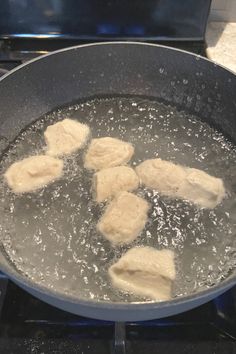 four pieces of meat are cooking in a pan on the stove top with water and oil