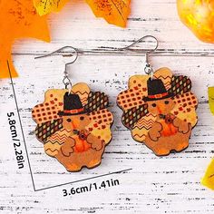 a pair of earrings with an image of a turkey wearing a top hat on it