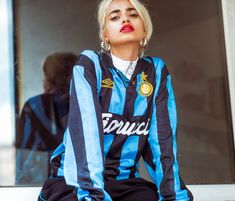 a woman sitting on top of a window sill wearing a blue and black shirt