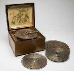 an antique music box with three silver plates in it