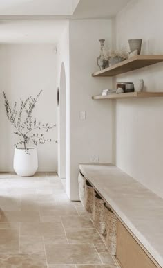 an empty room with some shelves and a vase on the wall