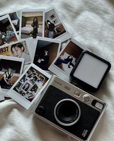 a camera and some polaroid pictures on a bed