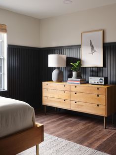 a bed room with a neatly made bed and a wooden dresser next to a window