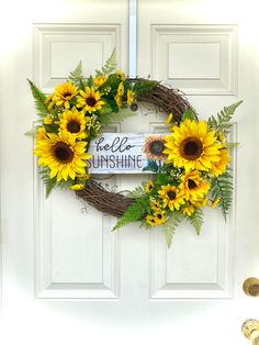 a wreath with sunflowers and greenery on it that says hello sunshine in front of a white door