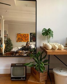 a mirror sitting on top of a wooden table next to a potted plant