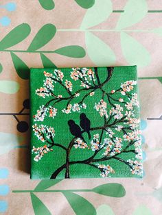 a small square painted with birds sitting on a tree branch