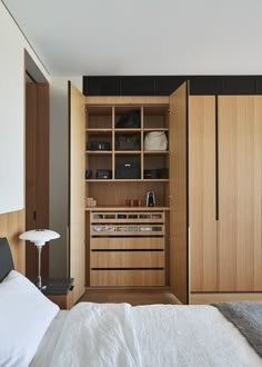 a bed sitting in a bedroom next to a wooden closet filled with drawers and shelves