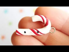 a hand holding a white and red striped keychain with black eyes on it