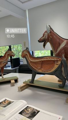 two wooden sculptures of animals on display in a museum