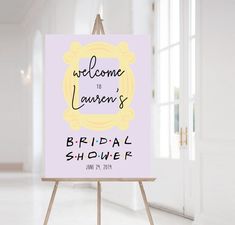 a welcome sign for a bridal shower is displayed on an easel in a white room