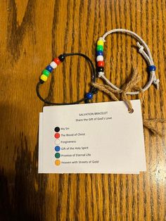 a wooden table topped with a card and two bracelets on top of each other