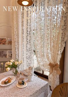 there is a table with flowers and tea cups on it in front of the window