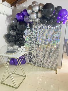 there is a table with balloons on it in front of a wall that looks like mosaic tiles